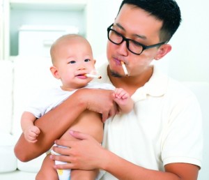 Asian family at home. Bad father smoking with baby together. Cig