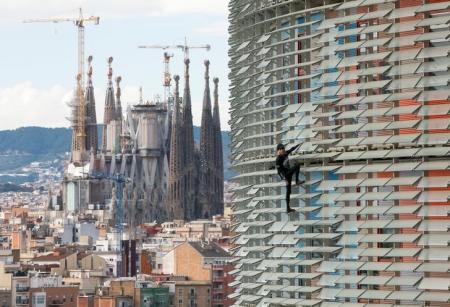 "الرجل العنكبوت" الفرنسي ألان روبير أثناء تسلقه ناطحة سحاب في برشلونة يوم الجمعة. تصوير: البرت خيا - رويترز.