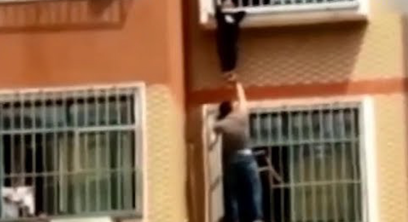بالفيديو... رجل شجاع ينقذ طفلا حشر رأسه بنافذة