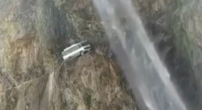 حافلة ركاب تسير على حافة جبل تحت شلال (فيديو)