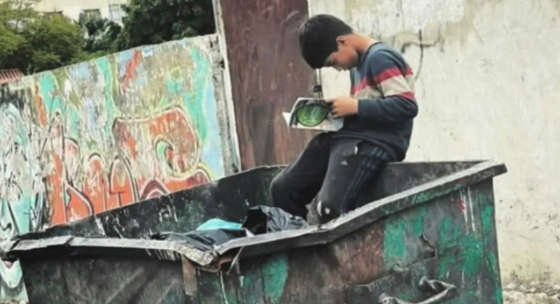طفل يقرأ كتاباً في حاوية القمامة.. قصة الصورة التي أشعلت عاصفة من التعاطف
